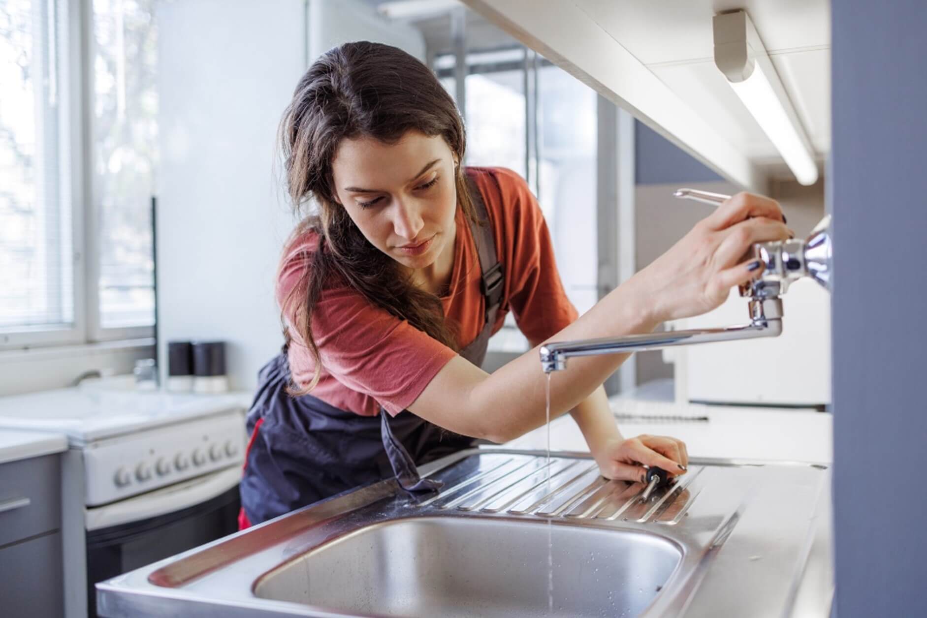 A woman repairs a kitchen sink, promoting water conservation in Phoenix