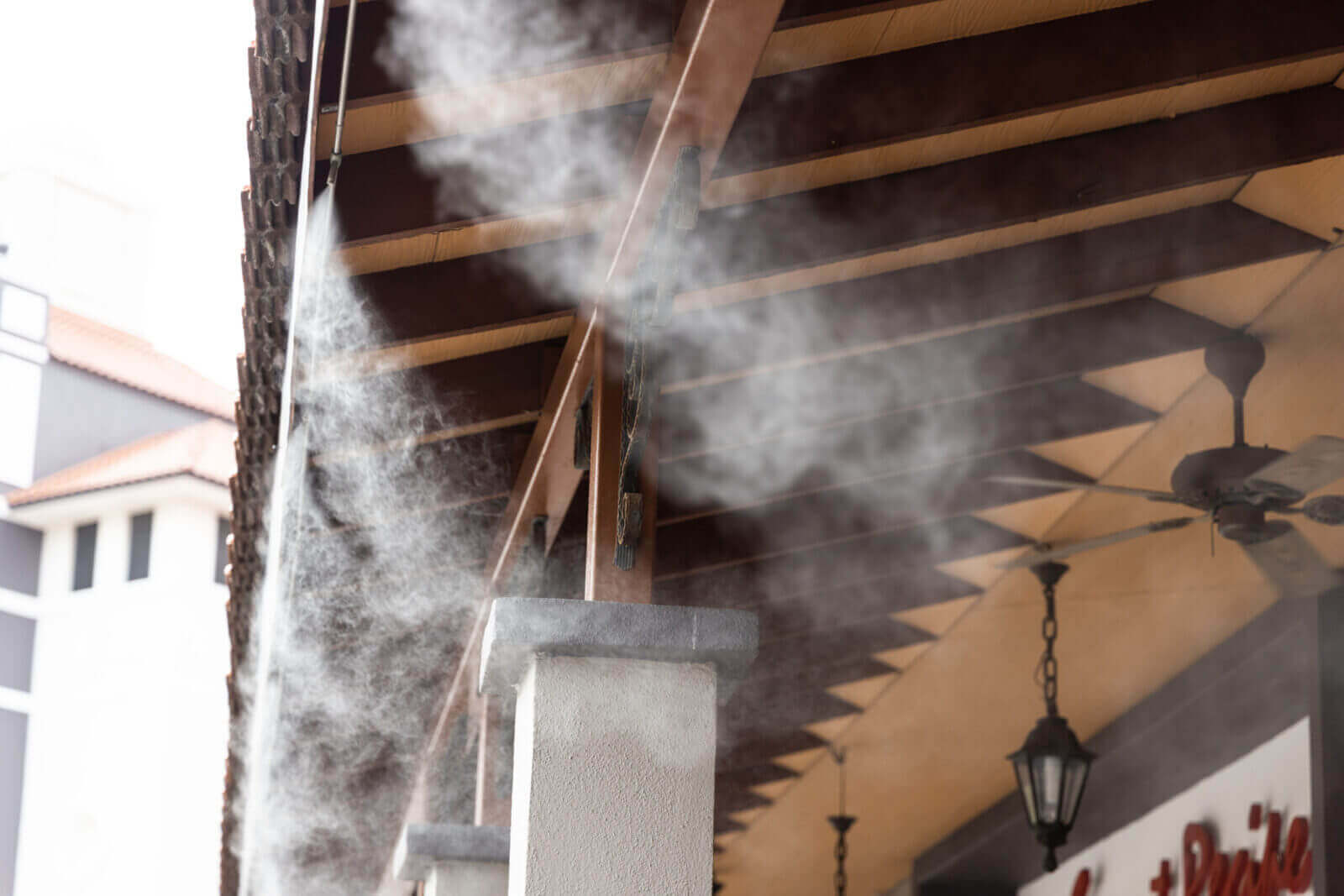 Outdoor patio misting system spraying fine cooling mist along roof beams in Phoenix, AZ