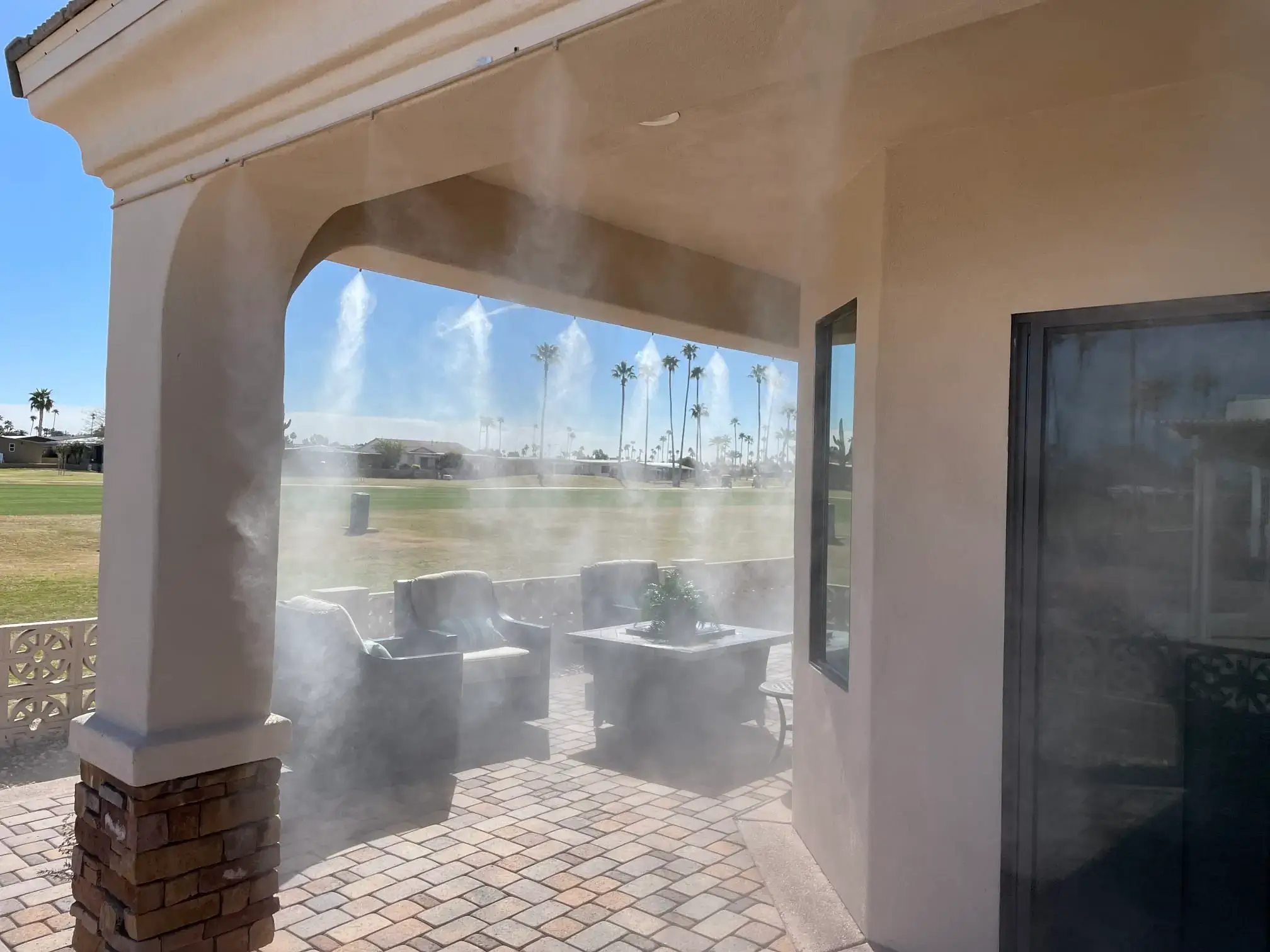 Covered patio with outdoor misting system cooling the seating area on a sunny day in Phoenix, AZ